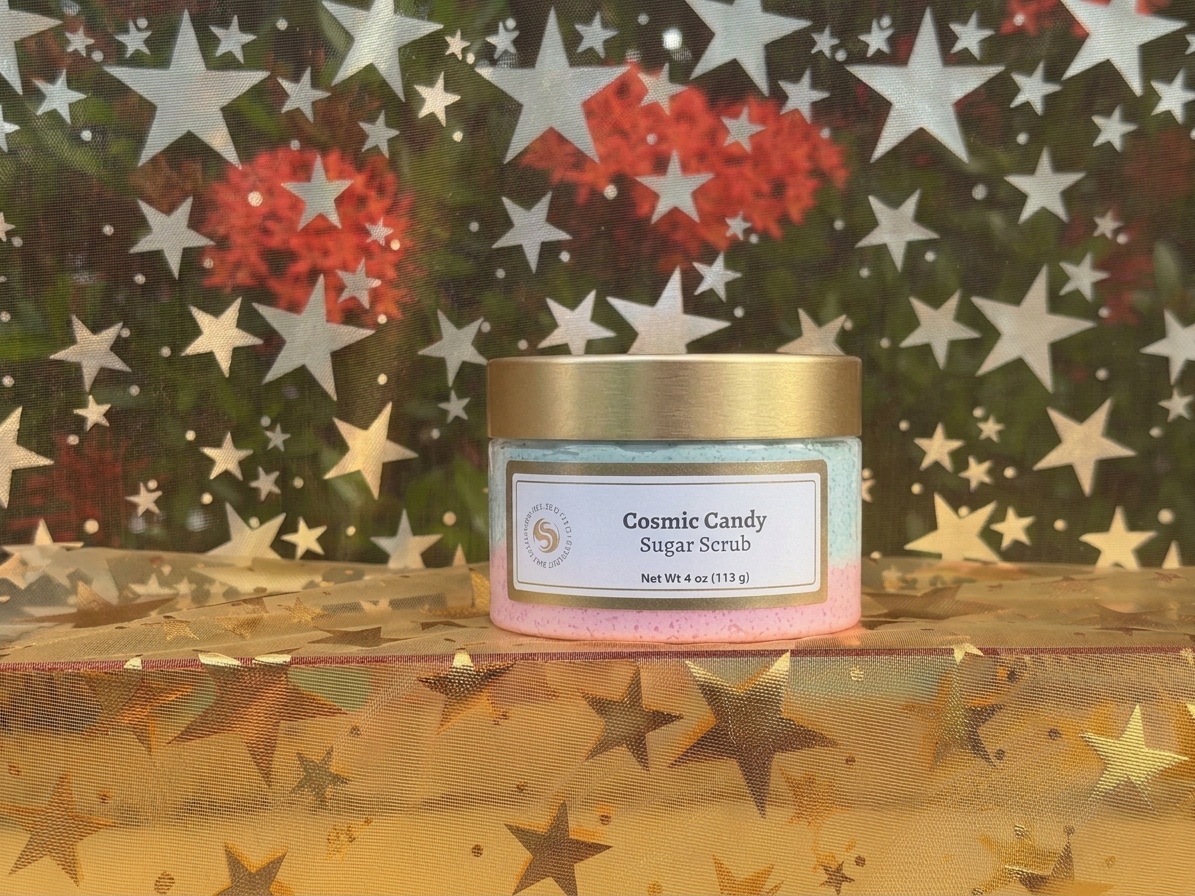 Cosmic Candy sugar scrub jar with teal and pink layers against a star-print fabric
